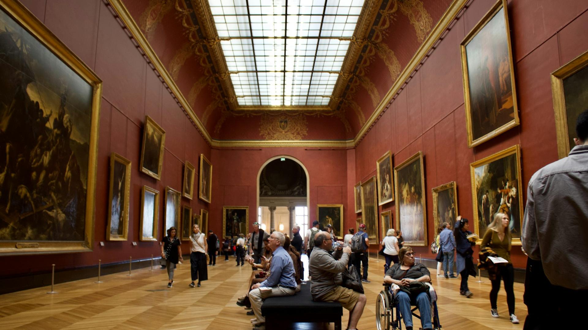 A group of people standing in a room filled with paintings