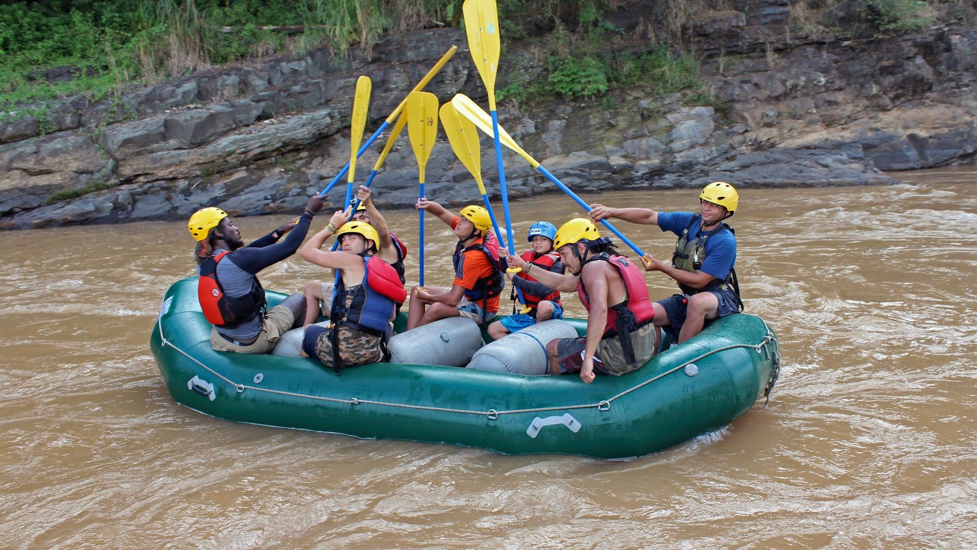 a group of people riding on the back of a raft down a river